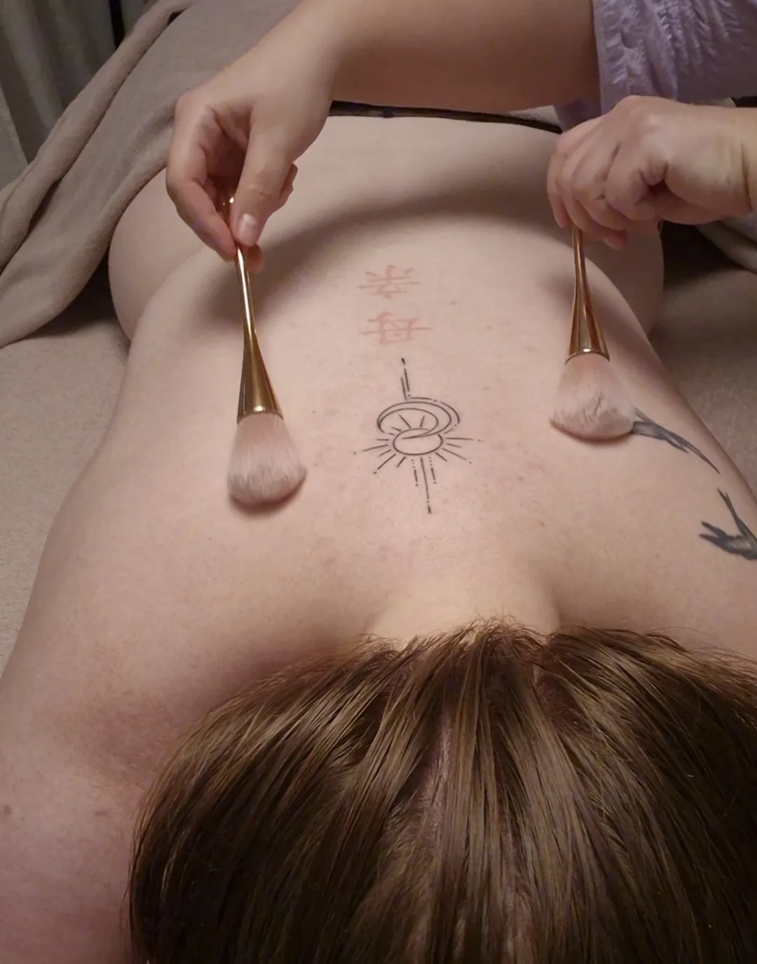 Caresse Sensorielle avec deux pinceaux dorés utilisés délicatement sur le dos